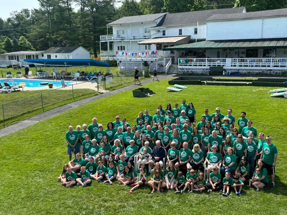 Family reunion group photo in matching green shirts on the lawn beside the pool at Gavin's